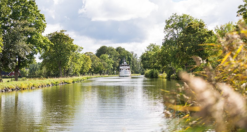 En vit passagerarbåt går i Göta Kanal in mot Töreboda